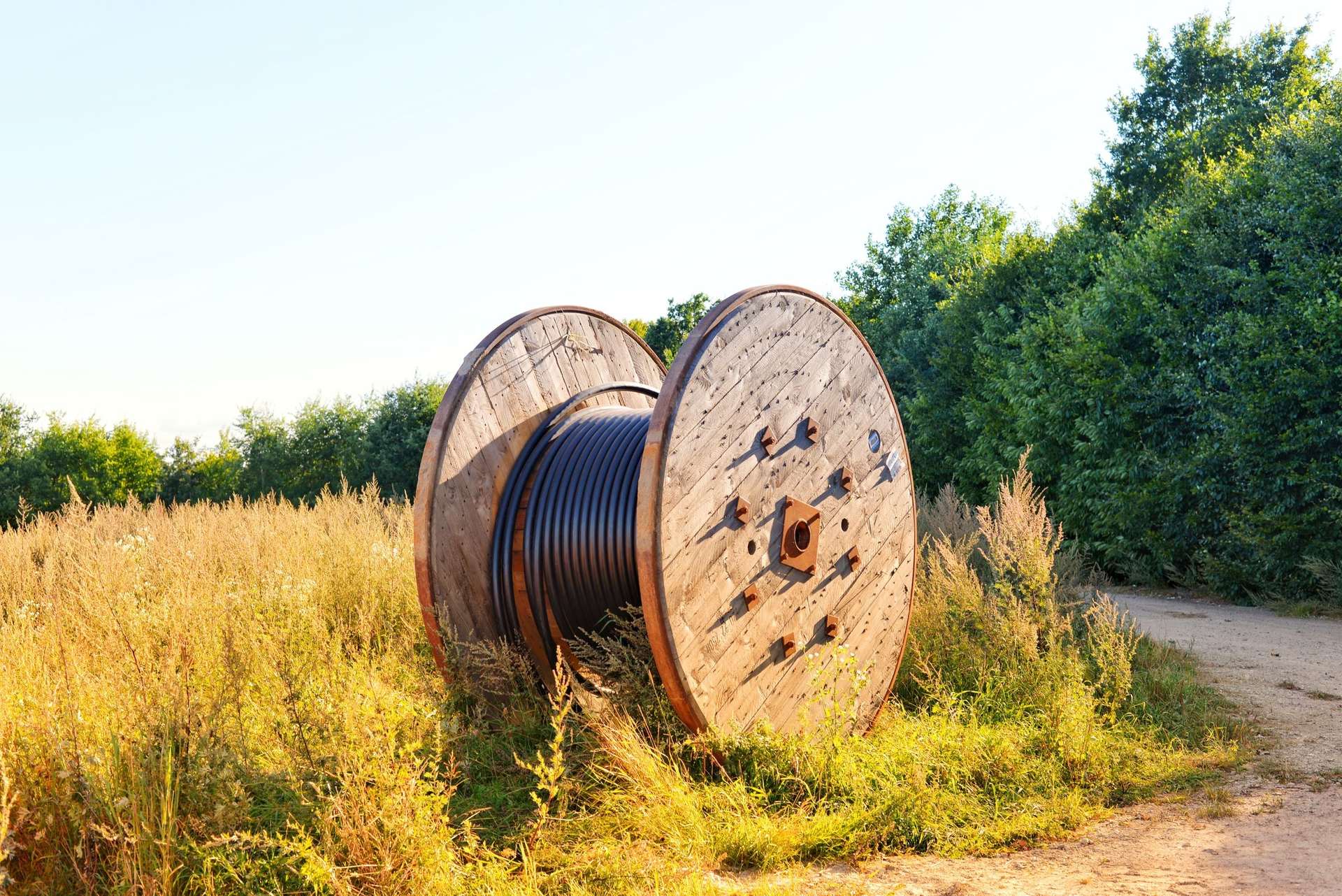 A reel of underground cable staged at the edge of a field