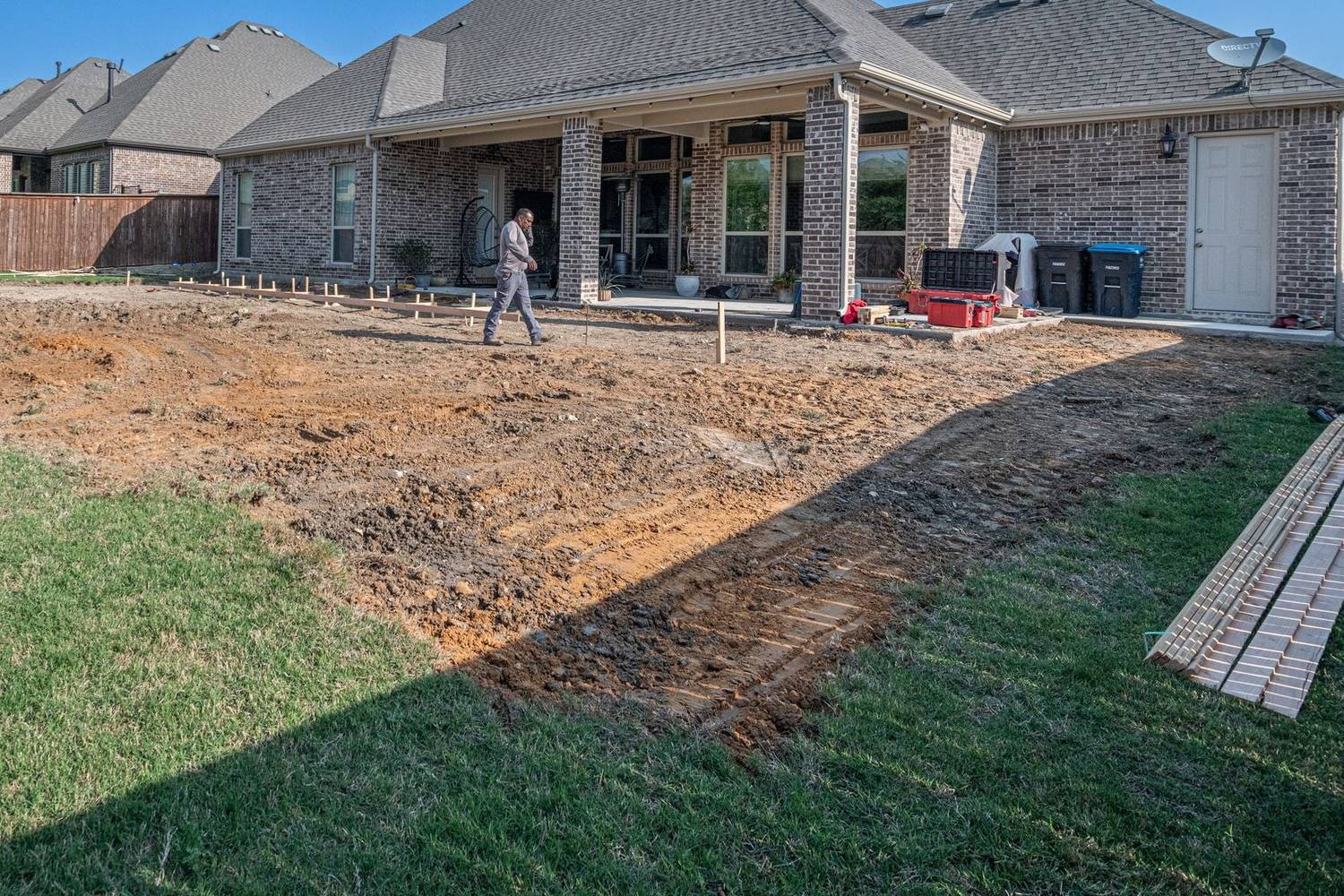 A graded yard with form stakes set behind a house