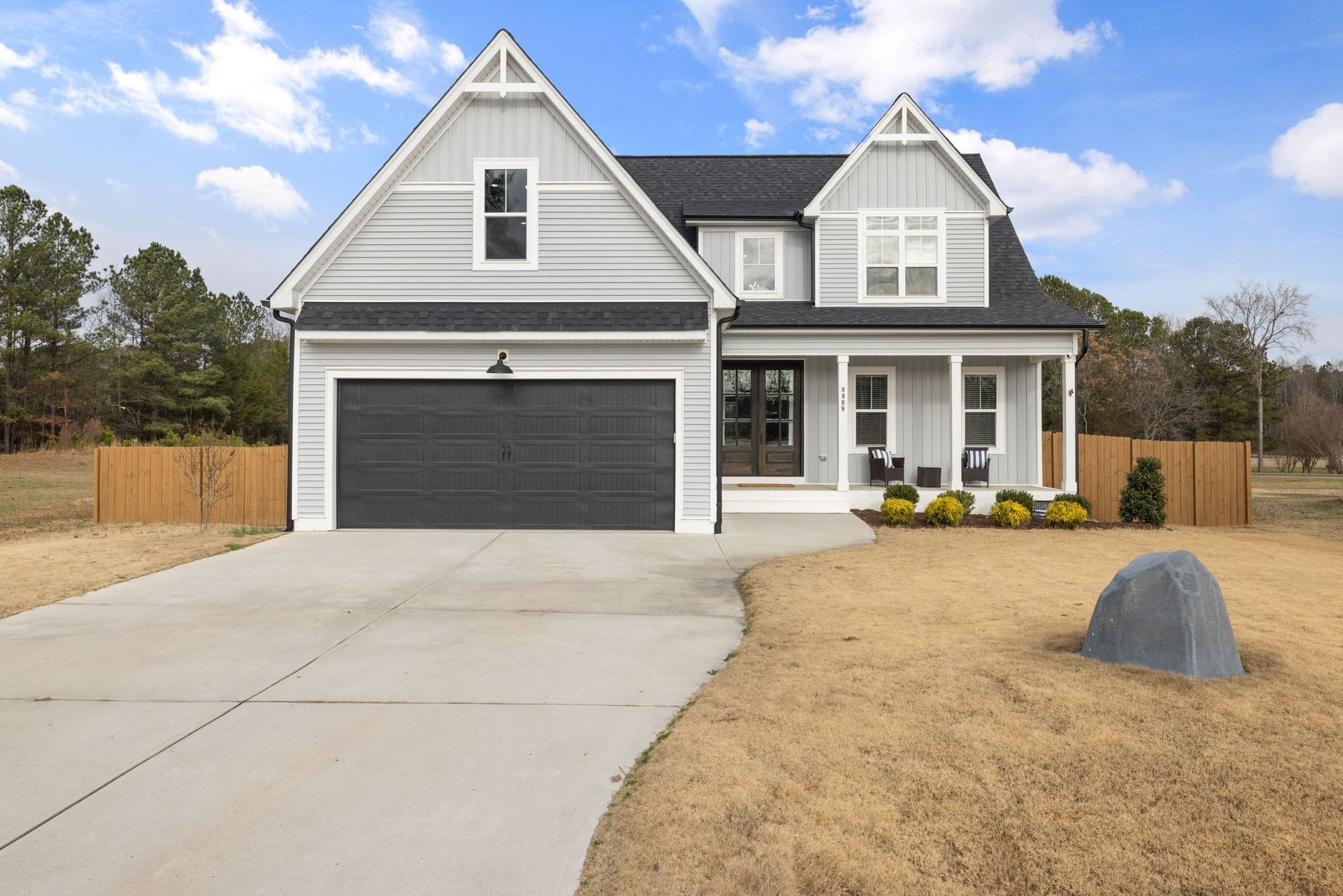 A new home with a fresh concrete driveway and a yard still at rough grade