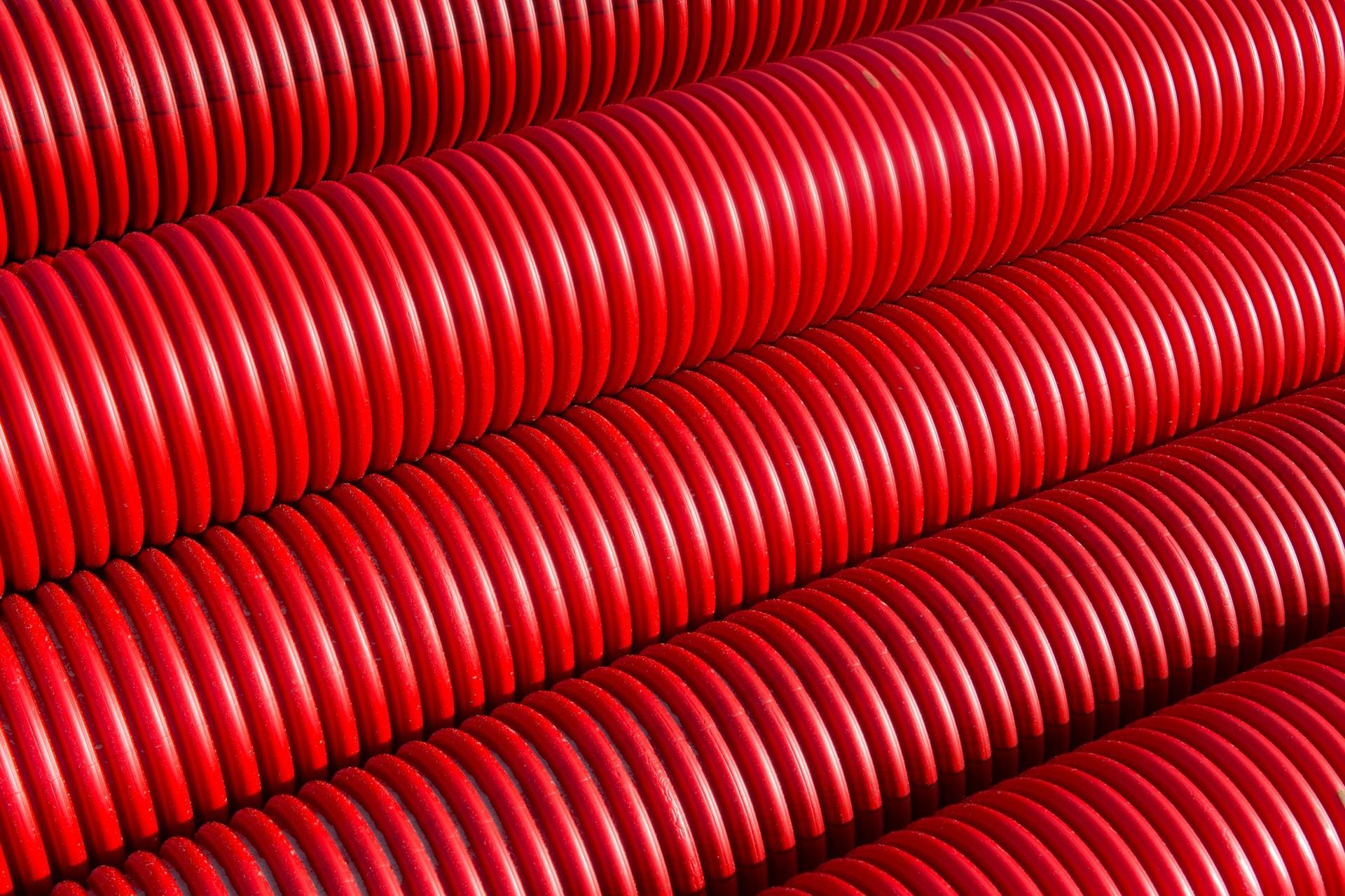 Red corrugated conduit stacked before it goes underground